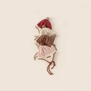 Kids knitted earflap beanies in four colors with pom-poms for winter warmth