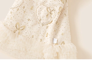 Detailed view of tweed toddler dress with pearl heart and sparkly sequin bow accents