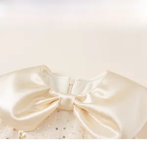 Detail of baby girl party dress featuring satin bow collar and sequin tweed fabric