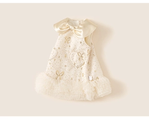Detailed view of cream-colored princess dress with tweed texture and golden sequined bows