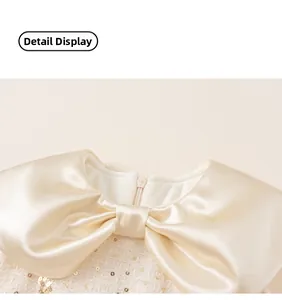 Detail of baby girl party dress with satin bow and golden sequin tweed fabric
