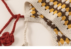 Detailed macro view of granny square crochet pattern with warm colors and floral drawstring