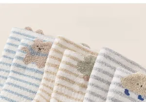 Close-up of thick striped coral fleece baby socks with cute cartoon bear patches