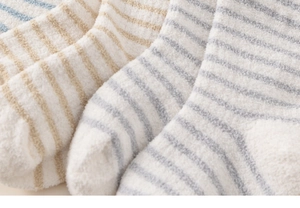 Close-up of soft coral fleece baby socks featuring classic colorful horizontal stripes