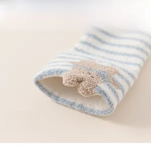 Detail of elastic cuff on warm striped toddler socks with a cute 3D cartoon bear ornament