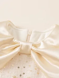 Elegant champagne tweed girls party dress with a satin bow and shimmering sequins