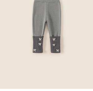 Détail de legging bébé gris avec poignets côtelés et trois petits nœuds blancs sur la jambe