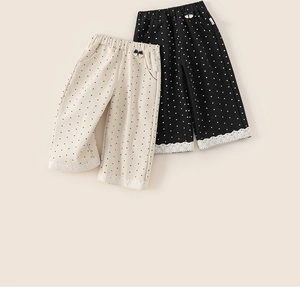 Detail of polka dot wide-leg trousers with elastic waistband and white lace trim at the hem