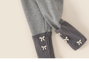 Détail de legging côtelé gris pour enfant avec nœuds blancs décoratifs et perles