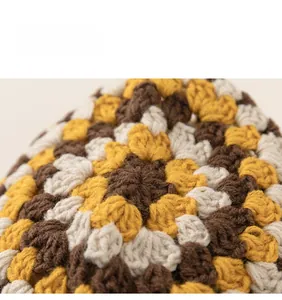 Close-up of retro floral crochet pattern in brown and mustard yellow knit fabric