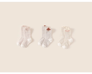 Detailed view of three pairs of striped baby socks with cute 3D animal and mushroom patches