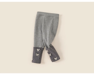 Détail de legging gris côtelé avec nœuds blancs décoratifs et revers de cheville foncés