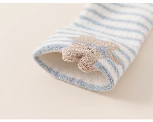 Close-up of soft coral fleece baby socks with blue stripes and a 3D plush bear detail