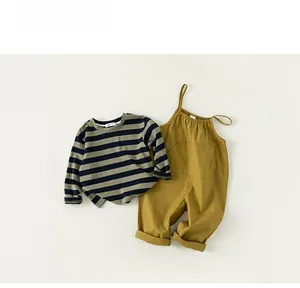 Flat lay of a striped long-sleeve tee and yellow overalls for baby boys