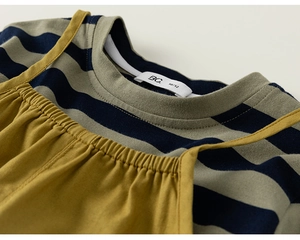 Detail of baby striped crewneck shirt and ginger yellow overall with soft cotton texture