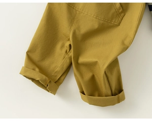 Detail shot of children's mustard yellow cotton trousers with folded hems and twill texture