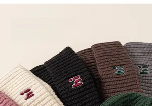 Close-up of thick knitted beanies in various colors with hi letter embroidery detail