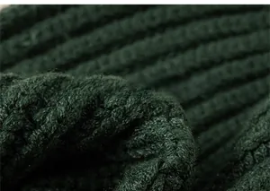 Detailed macro shot of thick dark green cable knit fabric with soft texture and patterns