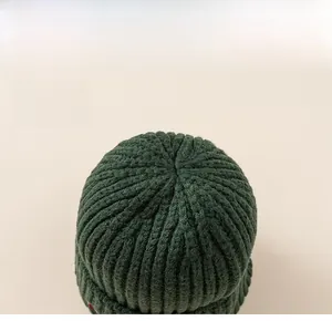 Detail view of thick dark green cable knit texture and sturdy top stitching of the warm winter hat