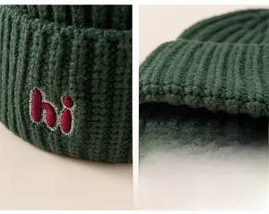 Detailed view of dark green knit hat featuring hi letter embroidery and ribbed texture