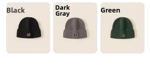 Detail view of knitted beanie hats in black, dark grey and green with hi embroidery