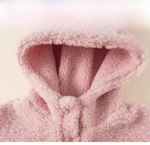 Gros plan sur la texture sherpa rose et le bouton en résine du sweat à capuche enfant
