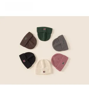 Flat lay of six colorful knit beanies with embroidered 'hi' logo for winter warmth