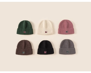 Detail view of colorful rib-knit beanies with 'hi' embroidery in six different colors