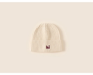 Detail of baby knitted hat showing oatmeal rib texture and red hi letter embroidery