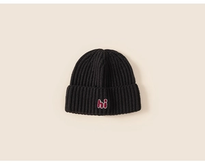 Close-up of black ribbed knit beanie for kids featuring hi letter embroidery detail