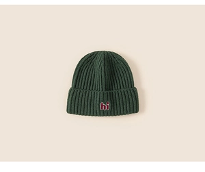 Detail of dark green knit hat with red 'hi' embroidery and thick ribbed texture