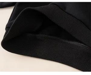 Detail view of black boys hoodie ribbed hem showing thick fleece lining for winter warmth