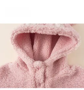 Gros plan sur la texture en polaire sherpa rose et le bouton du sweat à capuche enfant