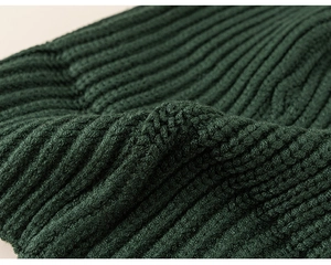 Detailed macro view of dark green ribbed knit fabric showing soft texture and thick yarn