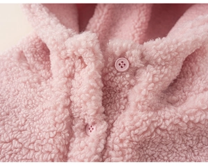 Détail du tissu polaire sherpa rose montrant la texture douce et le bouton assorti