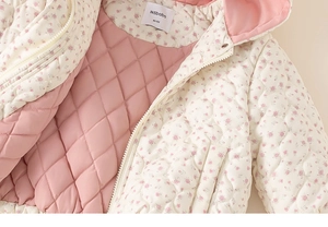 Detailed close-up of girls' floral quilted jacket showing soft inner lining and brand label