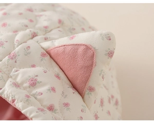 Detail of quilted floral baby jacket with 3D cat ears and soft pink plush lining