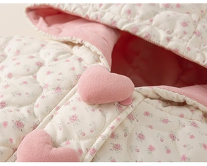 Close-up of girls floral quilted coat featuring pink heart button and soft fleece lining