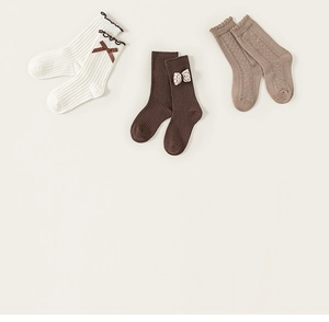 Detailed knit texture and ruffle cuffs of cotton children socks with bow accents
