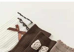 Detailed knit texture of children cotton socks with cute bows and wavy cuffs