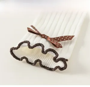 Detailed macro view of white ribbed cotton socks featuring brown lettuce trim and polka dot bow