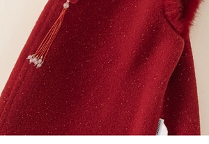 Détail du tissu en laine rouge avec pendentif à pompon et étiquette sur robe fille