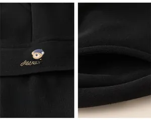 Detail of children black fleece trousers showing cartoon bear embroidery and side pocket