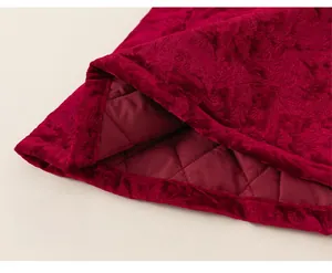 Makroaufnahme von rotem Samt-Jacquard-Stoff und warmem Steppfutter am Kinderkleid