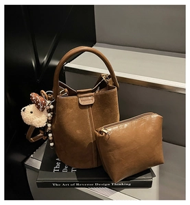 Detail of caramel suede bucket bag with inner pouch, white stitching and plush charm