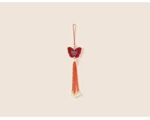 Détail de broderie papillon rouge avec perle et pompons perlés de style chinois