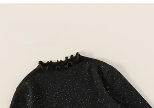 Close-up of black knitted girl's top with silver glitter and ruffled lettuce collar detail