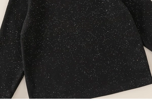 Close-up of black long-sleeve girl's top featuring a shimmering starry sparkle pattern