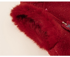 Détail de la manche d'une robe d'hiver rouge avec bordure en fourrure et broderie papillon