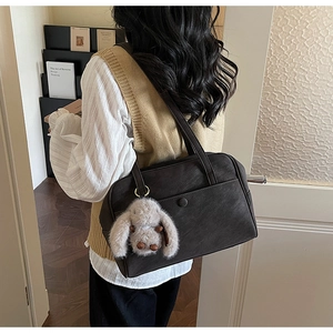 Retro dark brown leather Boston bag with plush rabbit charm shown on a stylish model